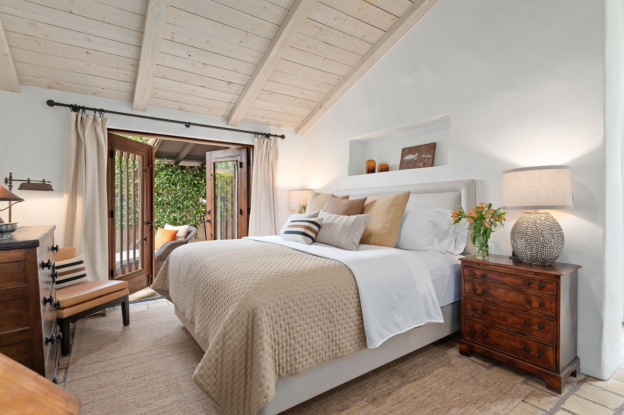 Une chambre à coucher avec un lit, une commode en bois et une table de chevet avec une lampe.