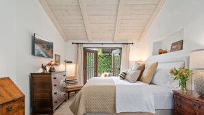 A bedroom with a bed, wooden dresser, and a window with curtains. - Luxurious Garden Home Walking Distance to Downtown SB (Santa Barbara)