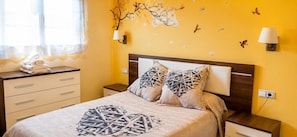 Une chambre d’hôtel avec un lit, deux tables de chevet, une commode et une fenêtre avec des rideaux.