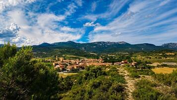 Un paysage montagneux avec un village aux bâtiments d’architecture traditionnelle, entouré de verdure et sous un ciel dégagé.