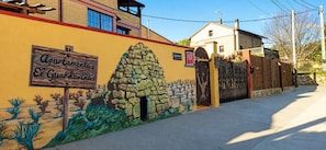 A building with a sign reading 'Apartamentos El Guardiánes' and a stone wall with a gate.