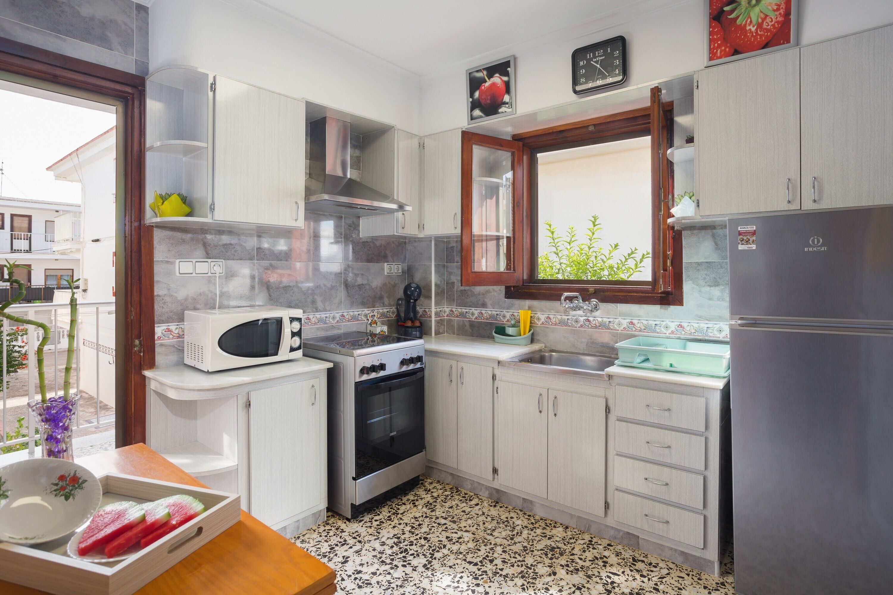 A kitchen with white cabinets, a microwave, stove, oven, and a refrigerator.