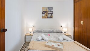 Ein Hotelzimmer mit einem Bett, Nachttischen, einem Gemälde, einem Holzschrank und einem Tablett mit Blume und Tassen.