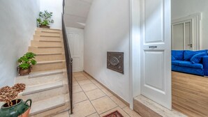 A staircase leading to a room with a blue sofa, a potted plant, and a metal plaque on the wall. - Sanbiagioapartment with Balcony, Wi-Fi, and Air Conditioning (Lecce)