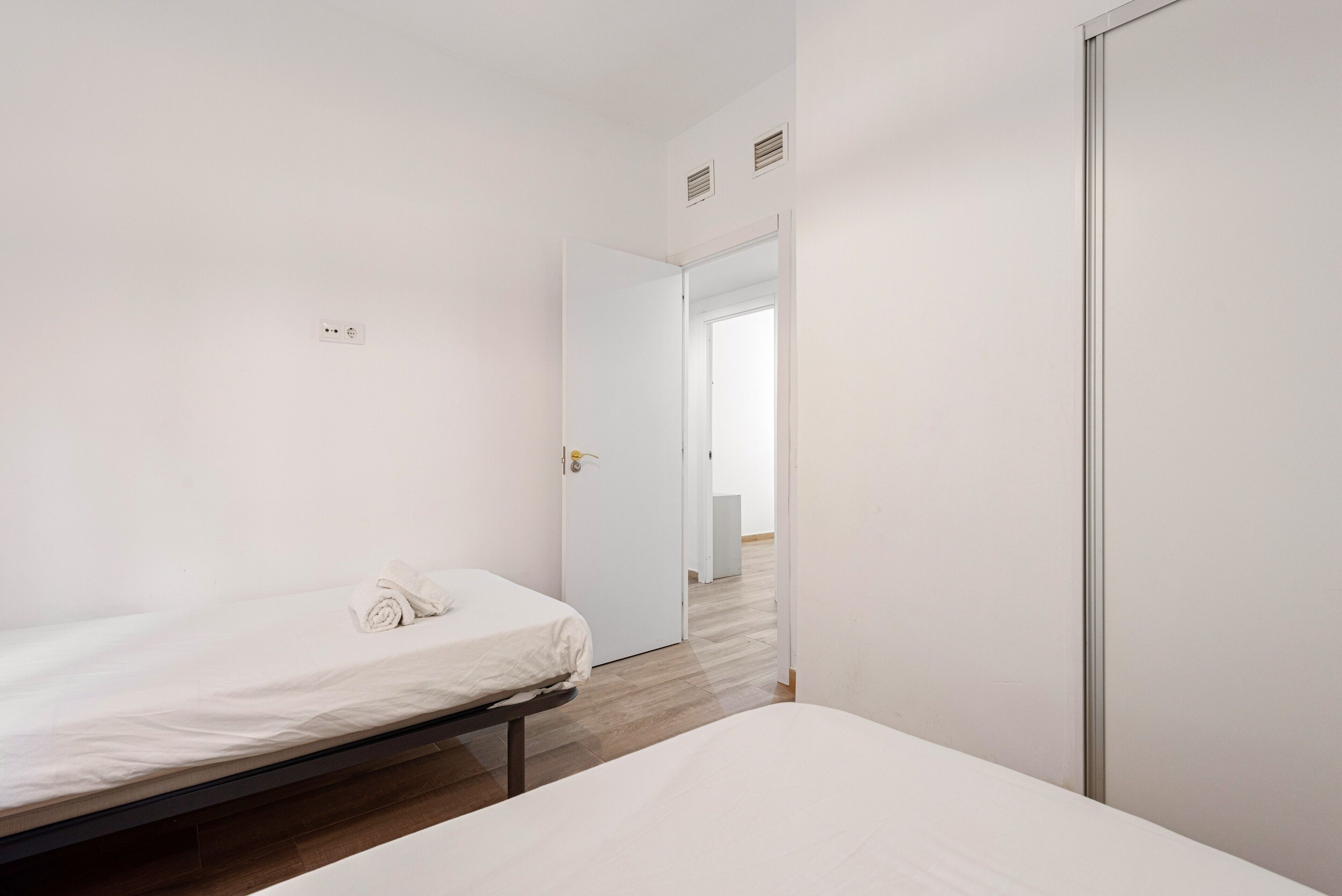 Een slaapkamer met een eenpersoonsbed, een deur naar een andere kamer en een zichtbare stopcontact.