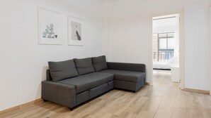Un salon moderne avec un canapé d’angle gris, un plancher en bois et deux œuvres d’art encadrées accrochées au mur.
