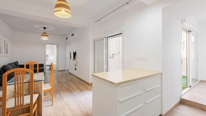 Une cuisine moderne avec une table et des chaises en bois, un plan de travail blanc et des luminaires suspendus.