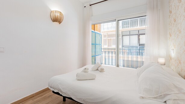 Une chambre à coucher avec un lit, une fenêtre donnant sur un beau paysage et un luminaire fixé au mur.