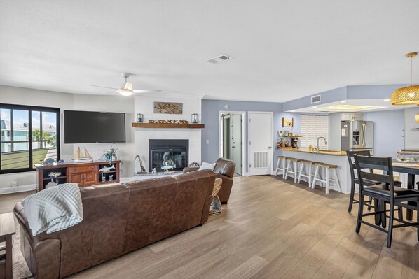 Een moderne woonkamer met een open haard, een televisie en een eethoek met barstoelen.