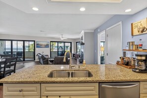 A modern kitchen with a granite countertop, stainless steel sink, and a coffee station.
