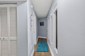 A hallway with light blue walls, white doors, and a blue rug. - Bayview Condo, Unit E - Anna Maria Island - 2 Bedroom/ 2 Bath bay view, maximum occupancy of 4 people. (Bradenton Beach)