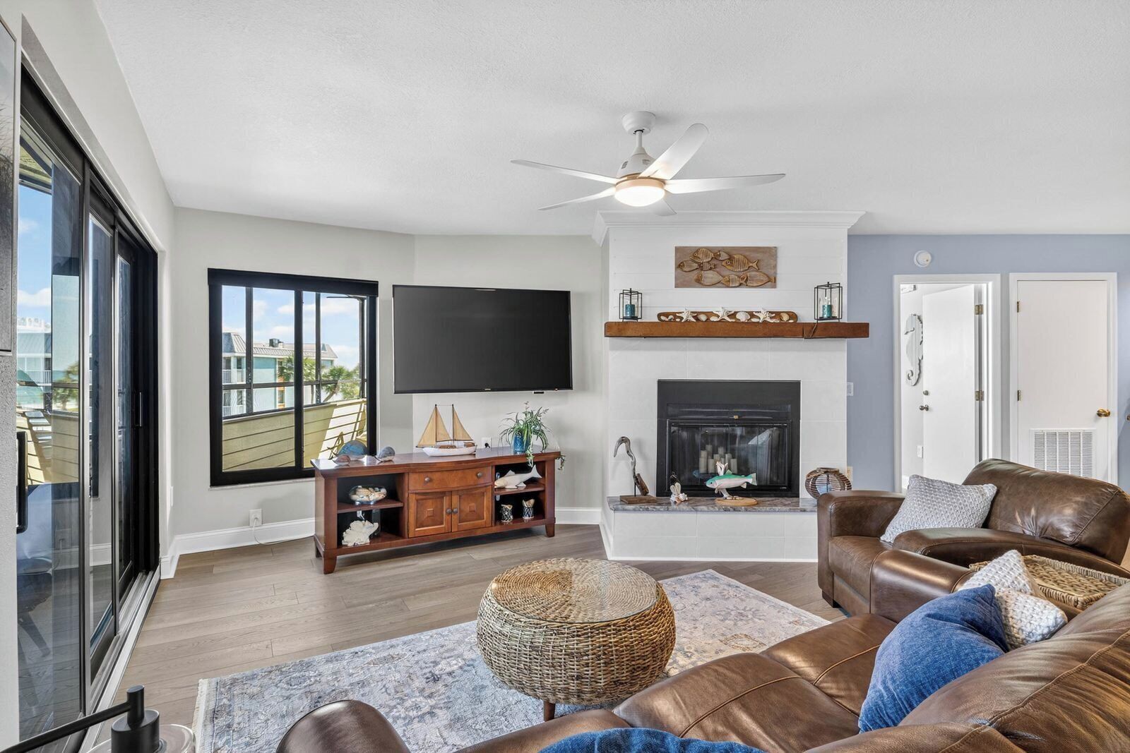 A living room with a fireplace, a television, and a ceiling fan.