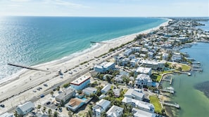 Vista aérea de un pueblo costero con propiedades frente a la playa, un muelle y un puerto deportivo.