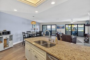 A modern kitchen with granite countertops, a built-in sink, and a dining area with a table and chairs.
