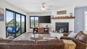 Una sala de estar con chimenea, televisor y un ventanal con vistas a un balcón.