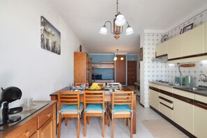 A dining area with a wooden table, chairs, and a kitchen in the background.