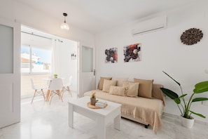 A modern living room with a sofa, a coffee table, and a dining area with chairs. - Apartment 'Rd Berrocal' with Wi-Fi and Air Conditioning (Málaga)