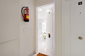 A hallway with a fire extinguisher mounted on the wall, a door labeled 'B', and a rug leading to a room. - Apartment 'Rd Berrocal' with Wi-Fi and Air Conditioning (Málaga)
