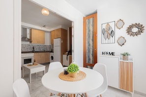 A modern kitchen with white cabinets, a marble countertop, and a dining area with a white table and chairs. - Apartment 'Rd Berrocal' with Wi-Fi and Air Conditioning (Málaga)