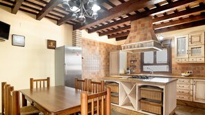 A kitchen with a wooden dining table, chairs, a built-in island, and a tiled backsplash. - Holiday Home 'El Cortijo' with Private Pool, Wi-Fi and Air Conditioning (Conil de la frontera)