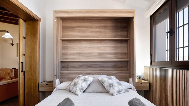 A bedroom with a bed, two nightstands, a wooden headboard, a window, and a door. - Holiday Home 'El Cortijo' with Private Pool, Wi-Fi and Air Conditioning (Conil de la frontera)
