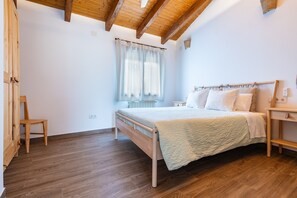 A bedroom with a wooden bed, a wooden chair, a window with curtains, and a wooden ceiling. - Country House 'Mas Del Sandungo' with Mountain View, Private Pool and Wi-Fi (Les Useras/ Useres)