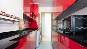 A narrow kitchen with red cabinets, a microwave, and a washing machine. - Casa de Bella Apartment with Balcony and Wi-Fi (Fuengirola)