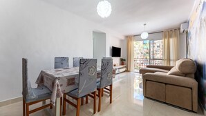 A dining area with a table and chairs, a sofa, a TV, and a balcony with a view. - Casa de Bella Apartment with Balcony and Wi-Fi (Fuengirola)
