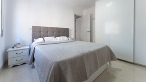A bedroom with a bed, a nightstand, a bedside table, and a wardrobe. - Casa de Bella Apartment with Balcony and Wi-Fi (Fuengirola)