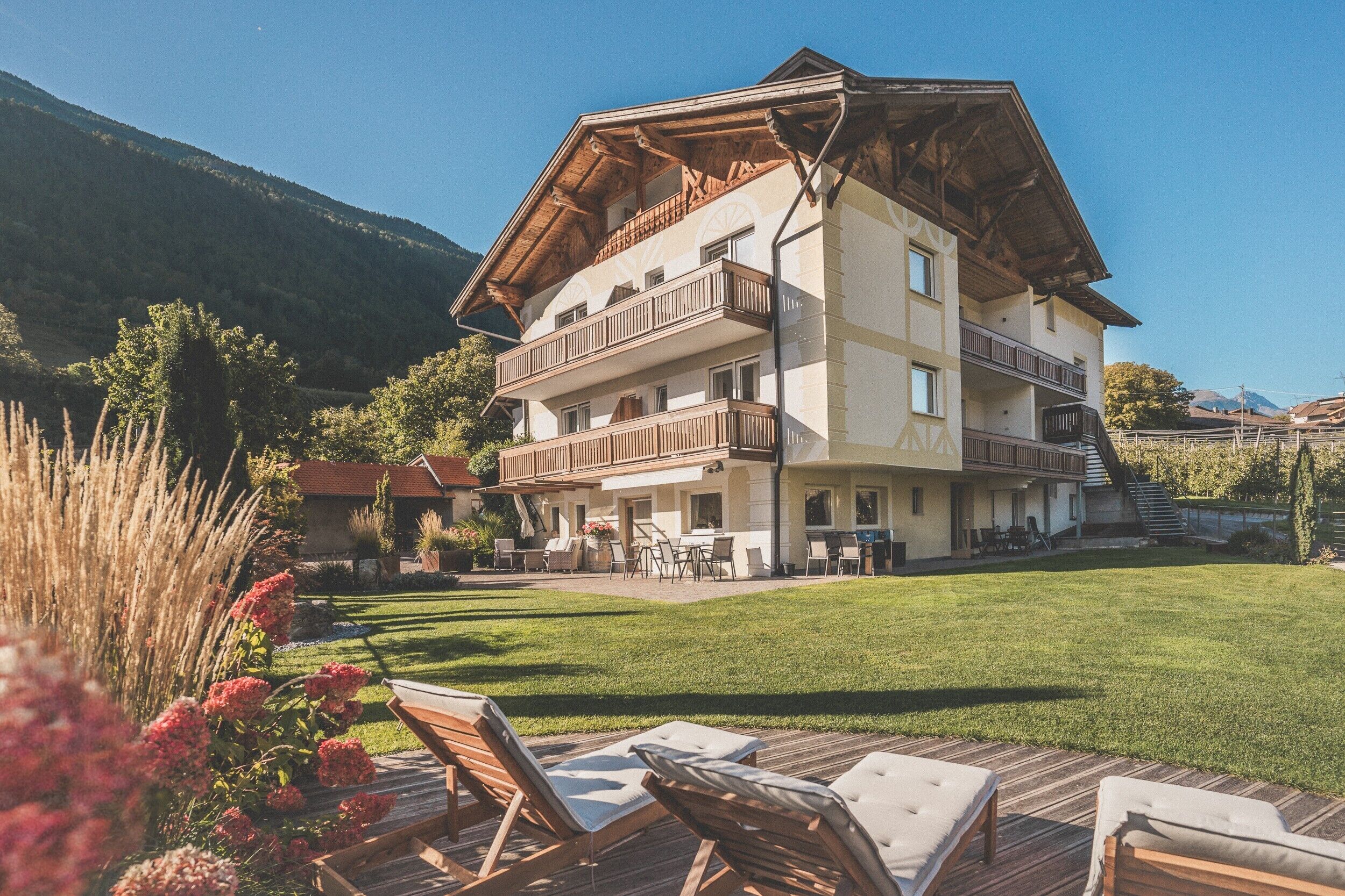 A multi-story building with balconies, a patio area with outdoor furniture, and a well-maintained lawn.