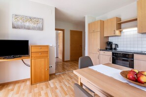Eine moderne Küche mit Holzschränken, einem Esstisch und einem Fernseher.