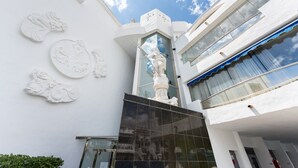 Un edificio moderno con una estatua, paredes blancas y grandes ventanales.