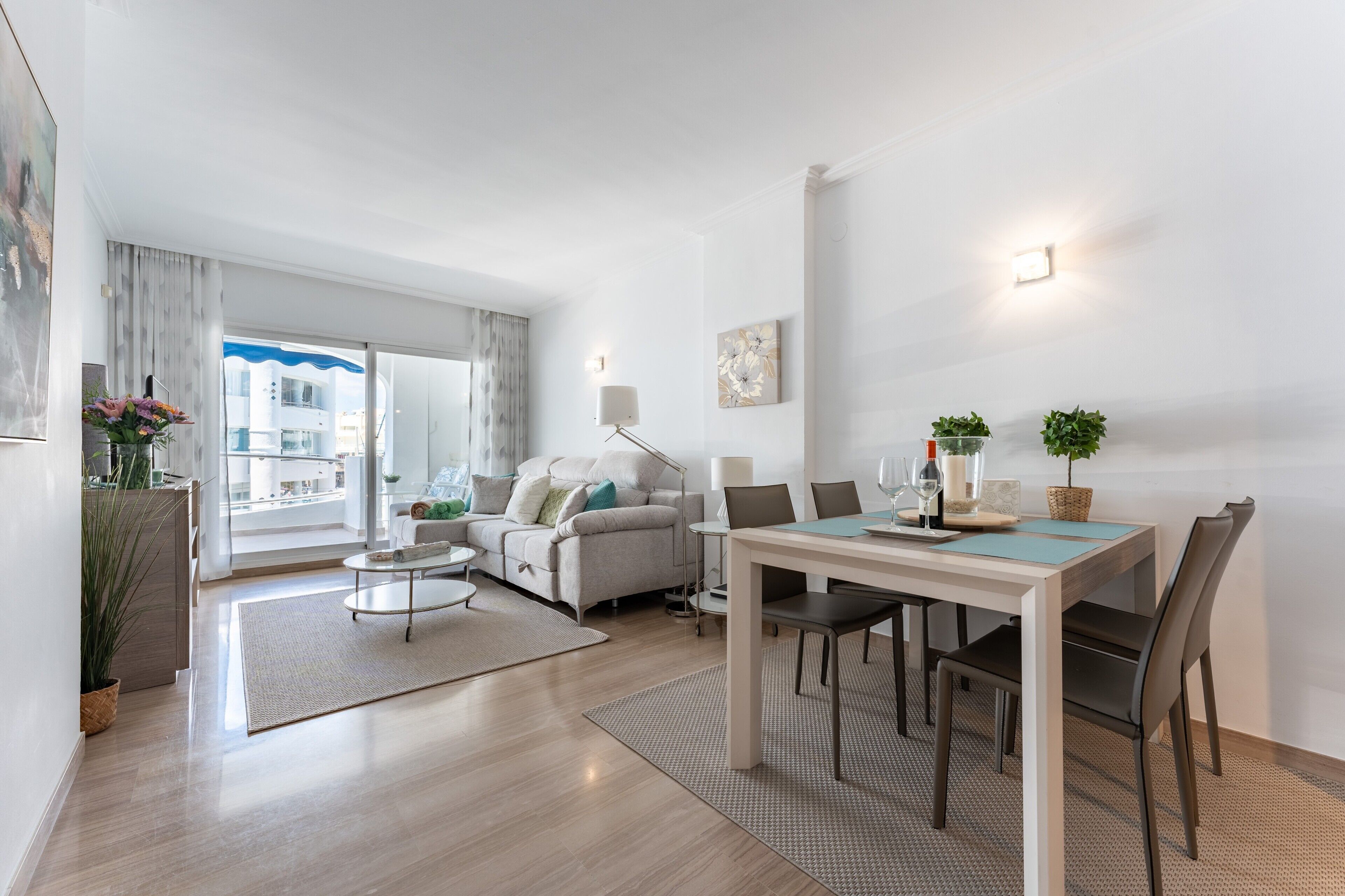 Ein modernes Wohnzimmer mit Essbereich, einer Couch, einem Couchtisch und Blick auf ein Gebäude.