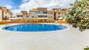 Una piscina rodeada de edificios de apartamentos con balcones y un cielo despejado.