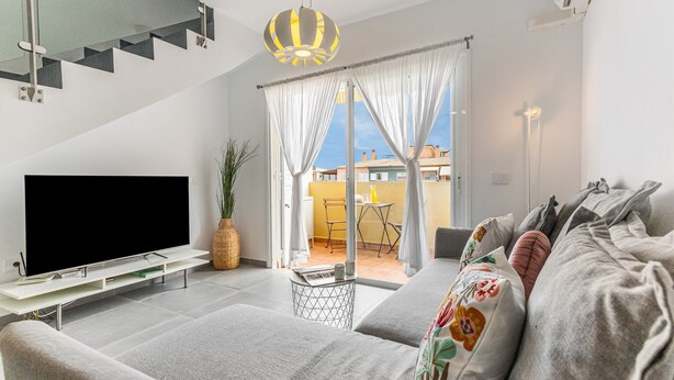 Una sala de estar moderna con un televisor de pantalla plana, un sofá gris y una mesita auxiliar.