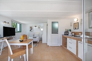 A compact living space with a dining area, kitchenette, and a bedroom with a bed and nightstand.