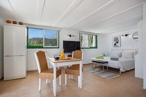 A compact living space with a dining area, a bed, a television, and a kitchen area.
