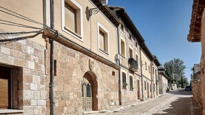 A cobblestone street lined with historic buildings featuring arched doorways and traditional architecture.