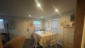 A dining area with a table and chairs, a bench, a cabinet with drawers, and a door. - Maple Creek Retreat (Owatonna)