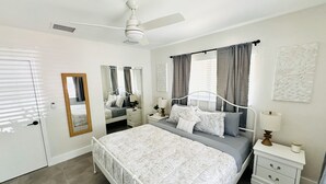 A bedroom with a bed, nightstands, a mirror, a ceiling fan, and a window with curtains. - Beautiful 3 Bedroom 3 Bath Home w/ Pool Access (Fort Lauderdale)