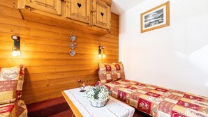 Ein gemütlicher Raum mit Holzwänden, einem gesteppten Bett, einer Bank mit einer Vase und einem gerahmten Bild an der Wand.