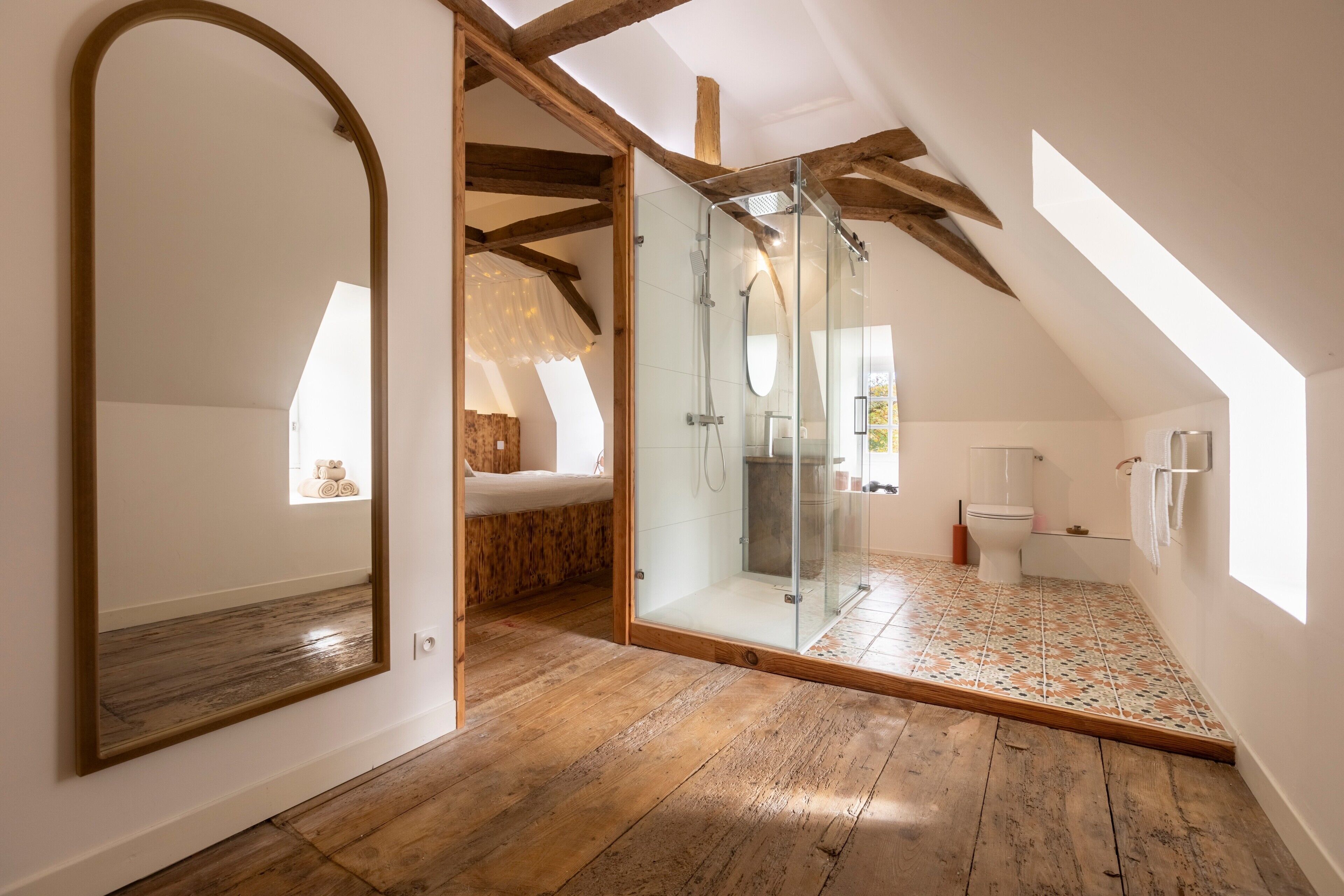 Een moderne badkamer met een glazen douche, houten vloer en een grote spiegel.