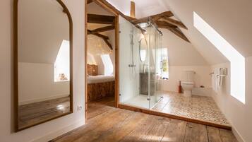 Een moderne badkamer met een glazen douche, houten vloer en een grote spiegel.