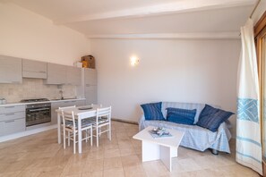 A modern kitchen with a dining area, a sofa, and a small table.