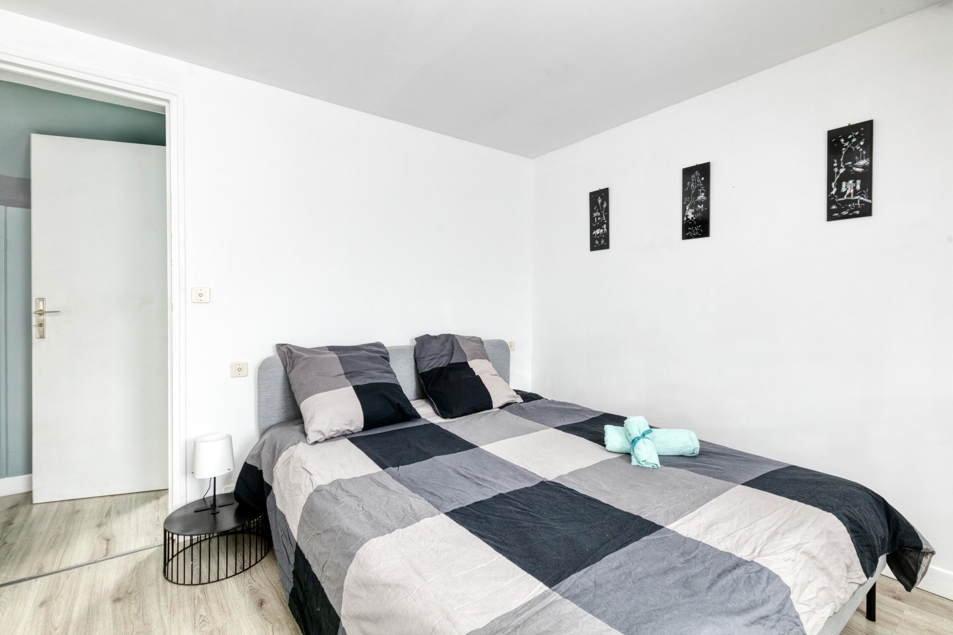 Une chambre à coucher avec un lit, une table de chevet, une lampe et une porte.