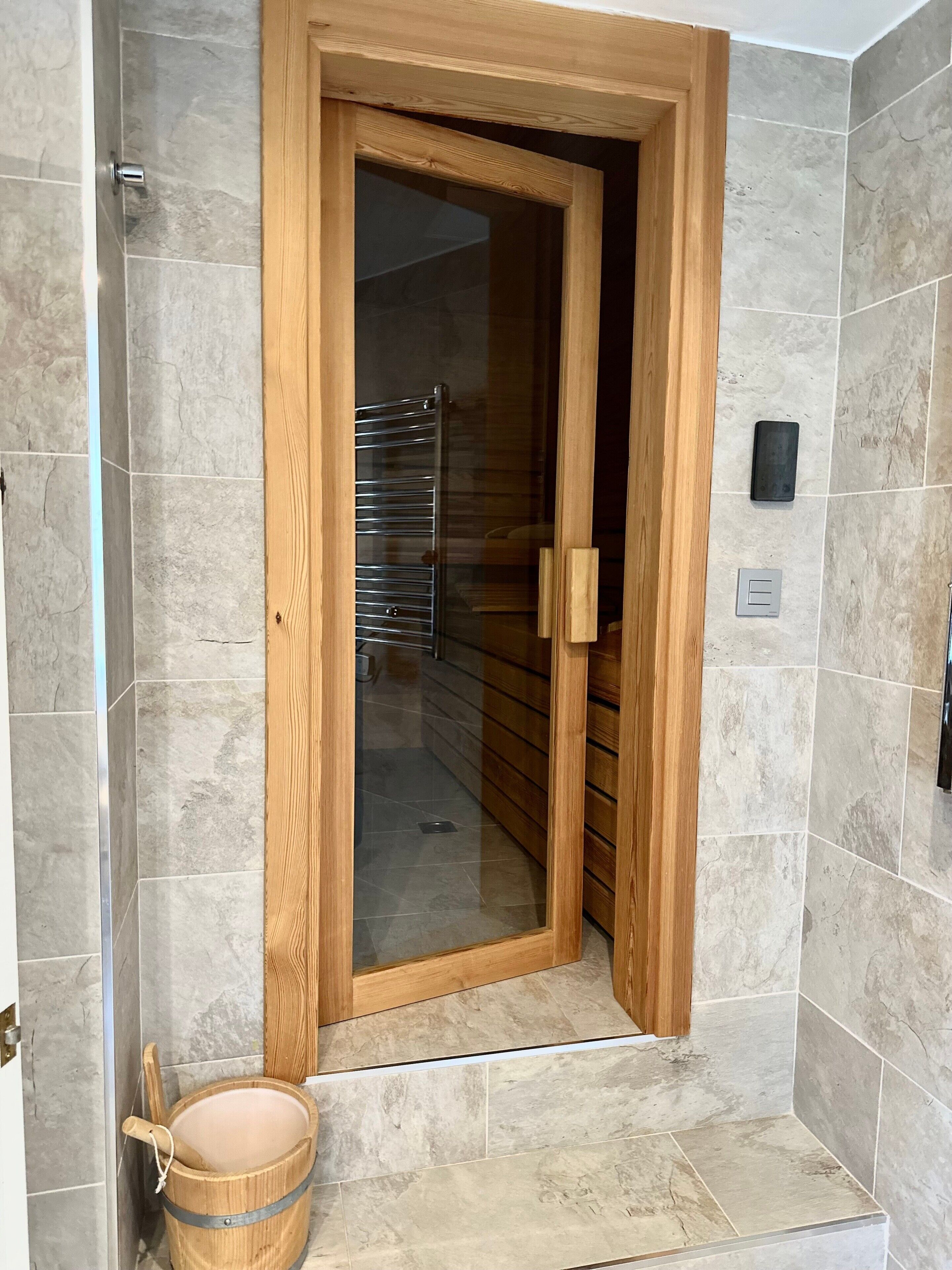 Une porte en bois avec un panneau de verre, un porte-serviettes en métal et un seau en bois.