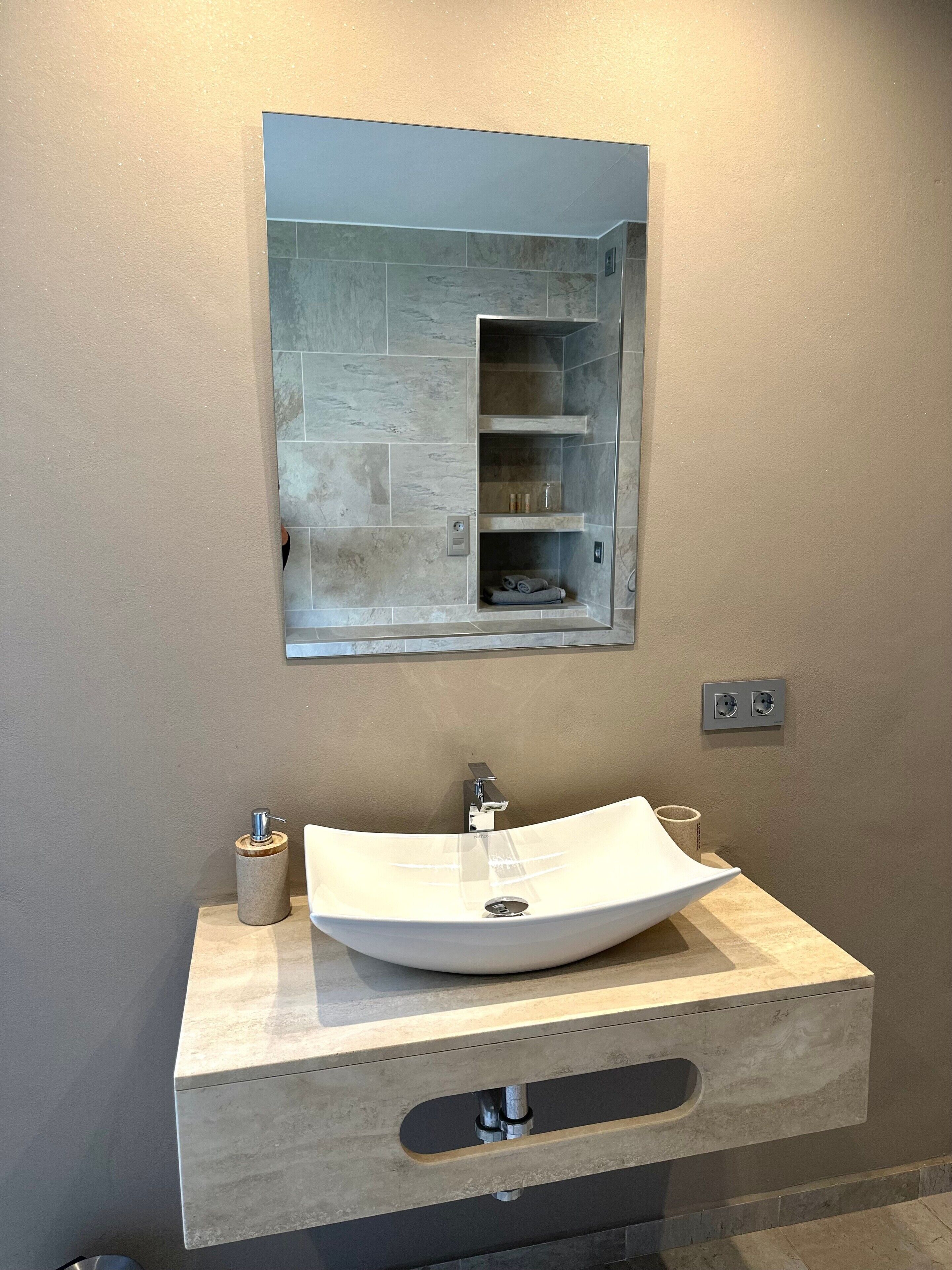 Une salle de bain avec un lavabo sur colonne blanc, un miroir au-dessus et un porte-serviettes.