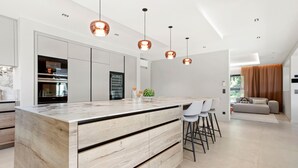 A modern kitchen with a wooden island, pendant lights, and a view to the living area. - Villa 'Belenos Piscine Vue Mer' with Sea View, Wi-Fi, and Air Conditioning (Roquebrune-sur-Argens)