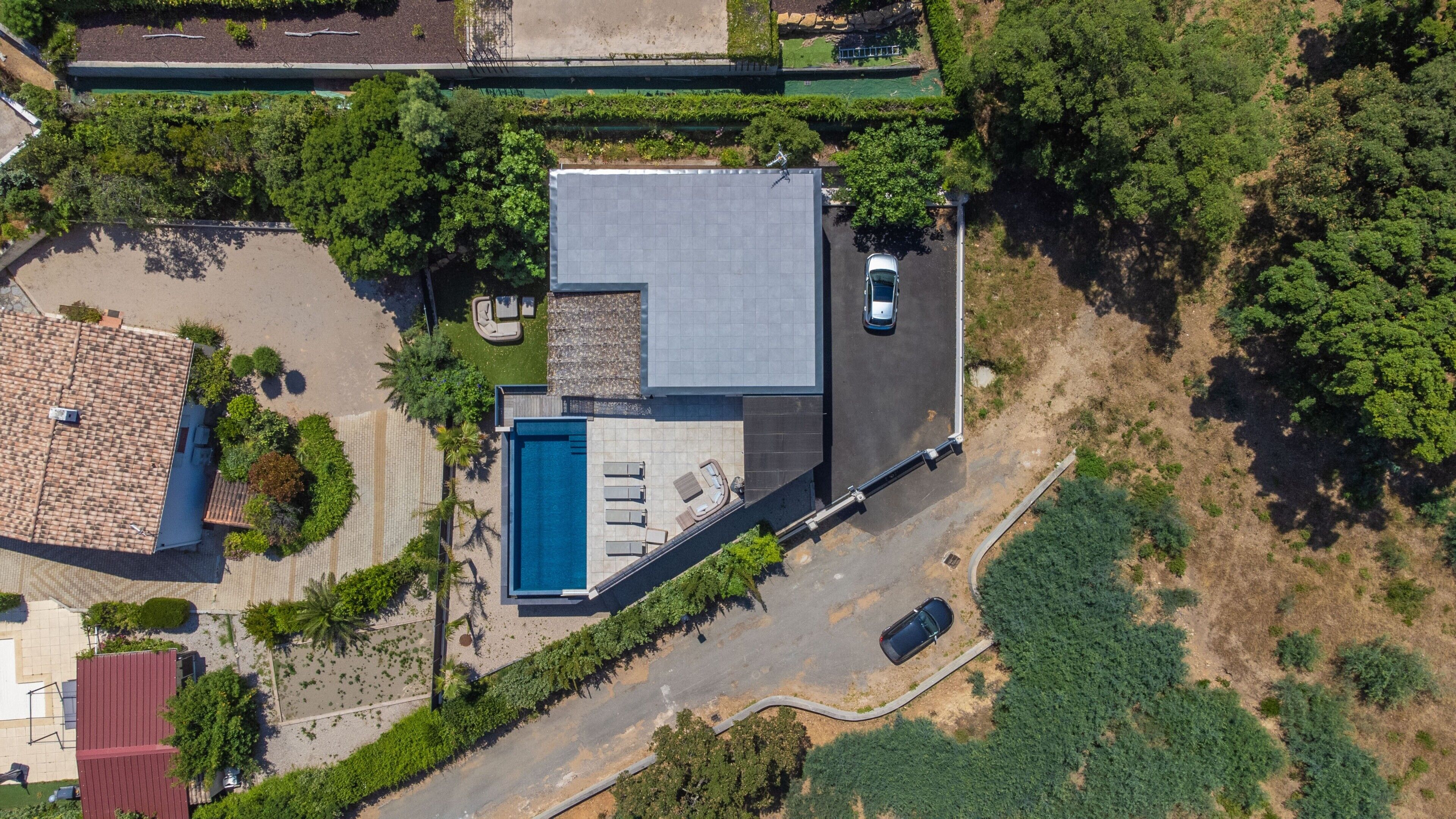 Luftaufnahme eines Wohnhauses mit Swimmingpool, überdachter Terrasse und Auffahrt.