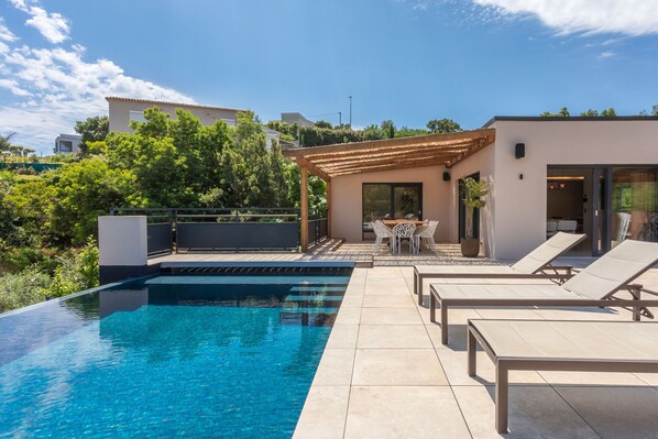 Una piscina con sillas de descanso, una pérgola y un patio.